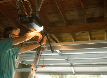 A Photograph of a Man Installing Metal Support For Lighting In a Garage